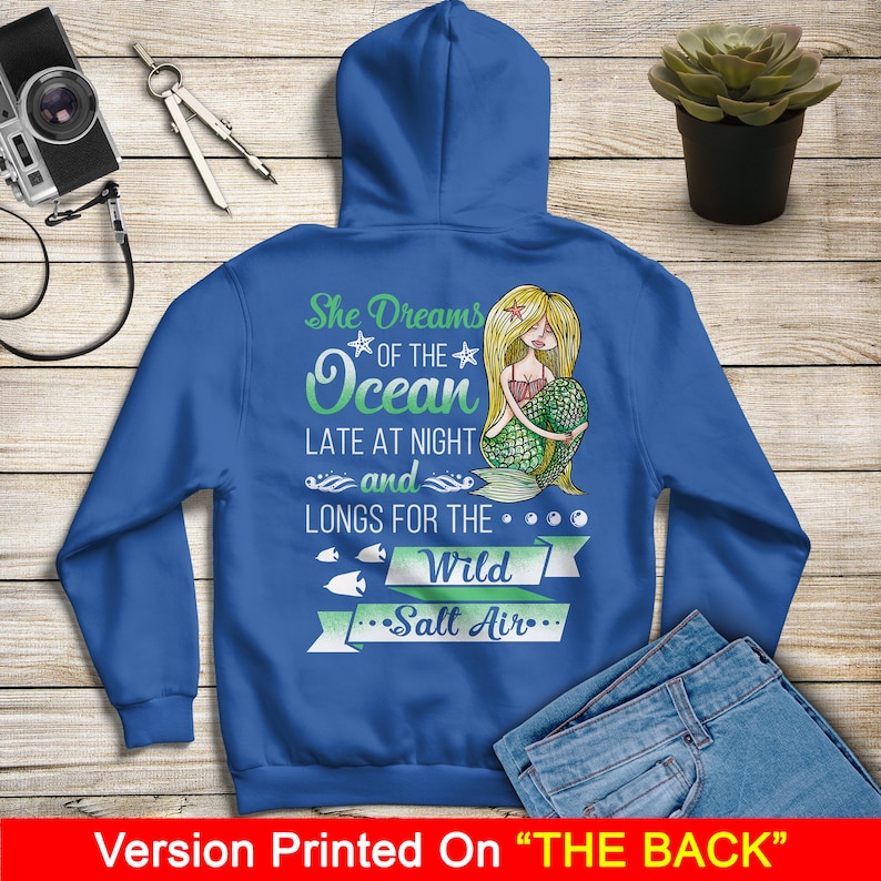 May include: A royal blue hoodie with a mermaid graphic and the text "She Dreams of the Ocean Late at Night and Longs for the Wild Salt Air".