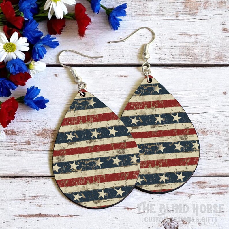Puede incluir: Pendientes en forma de l&aacute;grima con un dise&ntilde;o patri&oacute;tico. Los pendientes presentan un patr&oacute;n desgastado de rayas rojas y azules con estrellas blancas, evocando la bandera americana. Los pendientes tienen ganchos plateados.