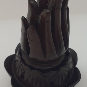 Op de afbeelding: Een donkerbruine houten wierookbrander in de vorm van een lotusbloem met een gesneden ontwerp. De bovenkant van de brander is gevormd als een vlam met meerdere punten.