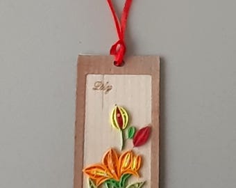 May include: A brown bookmark with a red ribbon attached. The bookmark features a paper quilling flower with orange, yellow, and green paper. The bookmark has the word "Dig" written on it.