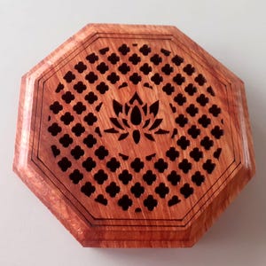 Könnte beinhalten: Achteckiger Holz-Räucherofen mit einem geschnitzten Lotusblumen-Design und einem Gittermuster. Der Räucherofen ist aus rötlich-braunem Holz gefertigt.