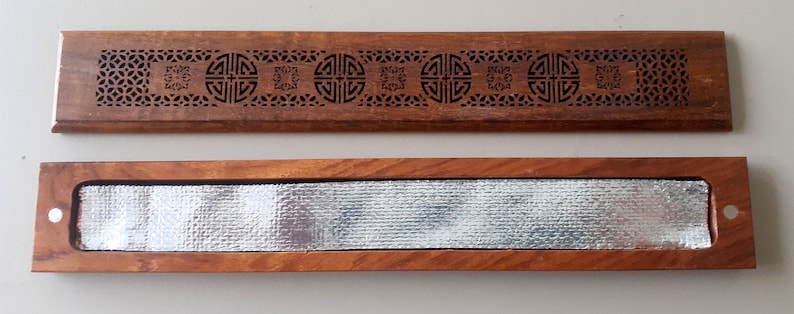 May include: A wooden incense holder with a decorative carved design and a removable metal insert. The holder is closed and the metal insert is visible.