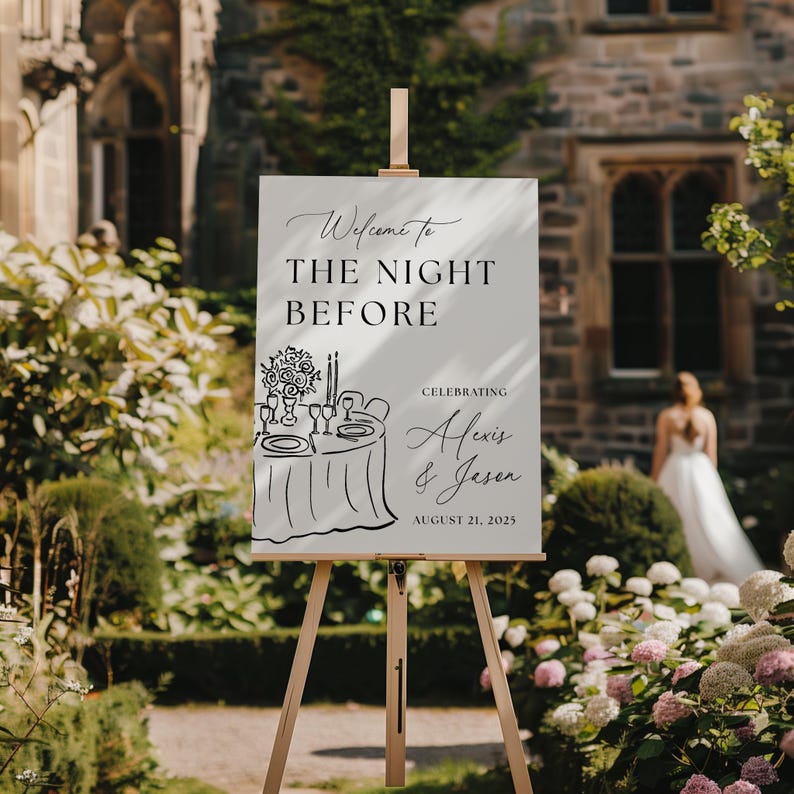 May include: A white sign on a wooden easel with the text "Welcome to The Night Before" and the names Alexis & Jason. The sign also includes a drawing of a table setting and the date August 21, 2025.