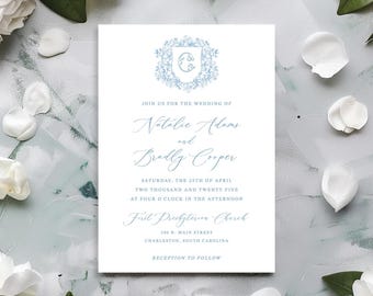 Puede incluir: Una invitación de boda con un escudo floral azul claro y una escritura elegante. La invitación incluye los nombres Natalie Adams y Bradly Cooper, junto con la fecha, hora y lugar de la ceremonia. Pétalos de flores blancas rodean la invitación.