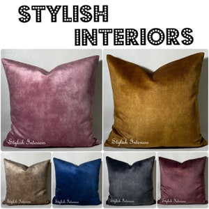 May include: Six velvet cushion covers in a range of colours, including dusty rose, mustard yellow, beige, navy blue, charcoal grey, and burgundy. The cushion covers are all square and have a subtle textured finish. The text "Stylish Interiors" is printed on the bottom of each cushion cover.