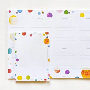 Può includere: Un set di planner settimanale e blocco note con un motivo a pois colorato ad acquerello. Il planner ha sezioni per lunedì, martedì, mercoledì, giovedì, venerdì e fine settimana. Il blocco note ha la parola "Note" in alto.