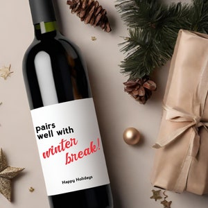 May include: A wine bottle with a white label that says "pairs well with winter break!" in red text. The label also says "Happy Holidays" in black text.