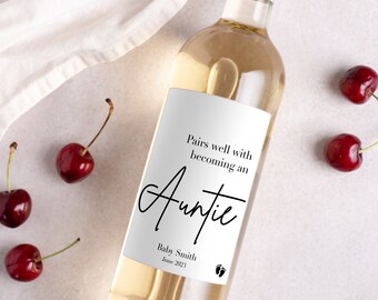 May include: A white wine bottle with a label that says "Pairs well with becoming an Auntie" and "Baby Smith June 2023". The label also has a pair of footprints.
