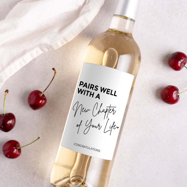 Pu&ograve; includere: Una bottiglia di vino bianco con un'etichetta bianca che dice "Pairs well with a new chapter of your life." e "Congratulations".