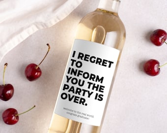 Op de afbeelding: Een fles witte wijn met een zwart-wit etiket waarop staat: "Het spijt me je te moeten informeren dat het feest voorbij is. Welkom in de echte wereld. Gefeliciteerd met je diploma!"