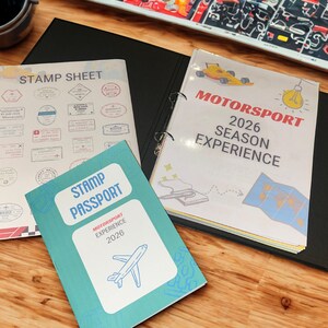 May include: A wooden desk displays a stamp sheet, a binder labeled "Motorsport 2026 Season Experience," and a teal "Stamp Passport" with an airplane graphic. The binder features a race car illustration.