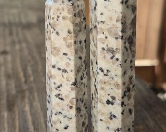 May include: Two white and gray granite crystal points with a hexagonal shape. The points are about 3 inches tall and have a speckled pattern.