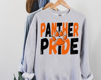 Può includere: Felpa grigia con testo nero e arancione che recita "Panther Pride" con una grafica di impronta di zampa in arancione.