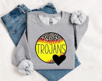 Op de afbeelding: Grijs sweatshirt met een gele softbal met een luipaardprint. De softbal heeft rode naden en het woord "TROJANS" erop geschreven. Een zwart hart bevindt zich naast de softbal.