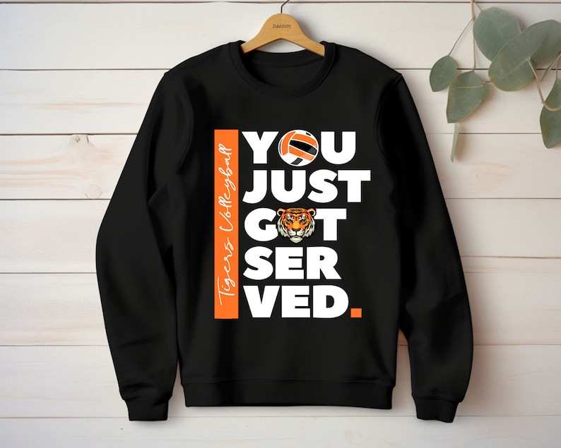Puede incluir: Sudadera negra con texto blanco que dice "You Just Got Served." Un bal&oacute;n de voleibol y una cabeza de tigre est&aacute;n incluidos en el dise&ntilde;o. El texto "Tigers Volleyball" est&aacute; en el lado de la sudadera.