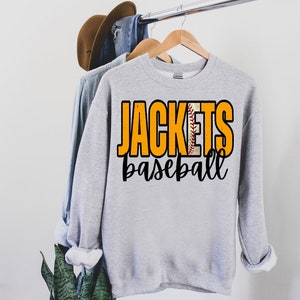 May include: Gray sweatshirt with the text "Jackets baseball" in black and orange lettering. A baseball with red stitching is incorporated into the word "Jackets".