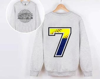 Pode incluir: Uma camisola cinzenta com um design de softball nas costas. O softball é amarelo com costuras vermelhas e um fundo de glitter azul. O número 7 está impresso no softball. A frente da camisola tem um design cinzento e branco com a palavra "Knights" impressa em branco.