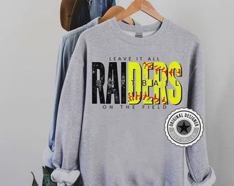 以下が含まれることがあります： 黒と黄色の「RAIDERS SOFTBALL」の文字がプリントされたグレーのスウェットシャツ。野球のステッチのディテールが施されています。メインテキストの上には「LEAVE IT ALL ON THE FIELD」の文字。右下には「BEST SELLER」のステッカーがあります。