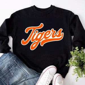 May include: Black sweatshirt with a white and orange "Tigers" graphic in a retro font.