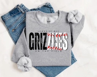 Puede incluir: Sudadera gris con el texto "Leave it all on the field" y "Grizzlies Baseball" en blanco y negro con un gráfico de béisbol.