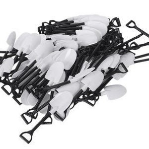 May include: A pile of black and white plastic toy shovels. The shovels are small and have a simple design.