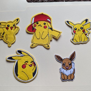 May include: Embroidered patches featuring Pikachu in various poses, including one wearing a red and white baseball cap. The patches are yellow, black, and red, with an additional patch of Eevee.