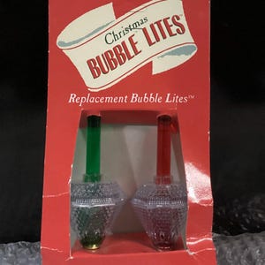 May include: A red cardboard package containing two replacement Christmas Bubble Lites. The packaging features the text "Christmas BUBBLE LITES" and "Replacement Bubble Lites". One light has a green stem and the other has a red stem.