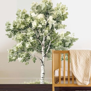 May include: Watercolor mural of a birch tree with green leaves and a white trunk. The tree is painted on a light beige wall. A wooden crib with a beige blanket is in the foreground.