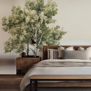 May include: A bedroom with a watercolor mural of a tree on the wall. The room features a wooden bed frame, nightstand, and bench. The bed is made with white linens and gray pillows. A black lamp and decorative items sit on the nightstand.