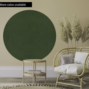 May include: A green circle wall decal with a textured surface, a wicker chair with a white cushion and a throw pillow, and a small wooden side table with a shelf.