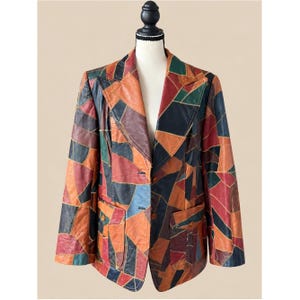 May include: A blazer constructed from multi-colored leather patches in shades of orange, red, dark green, blue, and black. The garment features a notched lapel, a two-button front closure, and two lower front pockets with buttoned flaps.