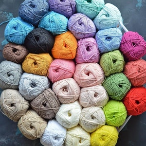 Puede incluir: Una colecci&oacute;n de ovillos de lana coloridos en varios tonos, incluyendo azul, morado, verde, naranja, rosa y amarillo. La lana est&aacute; cuidadosamente dispuesta, sugiriendo un proyecto de artesan&iacute;a o tejido. La imagen muestra una variedad de colores y texturas.