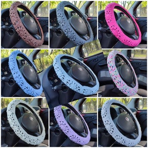 Puede incluir: Una colecci&oacute;n de fundas de volante de ganchillo en varios colores, incluyendo marr&oacute;n, gris, rosa, azul y lavanda. Cada funda presenta un patr&oacute;n floral y est&aacute; dise&ntilde;ada para adaptarse a un volante de coche est&aacute;ndar. A&ntilde;aden un toque decorativo al interior del coche.