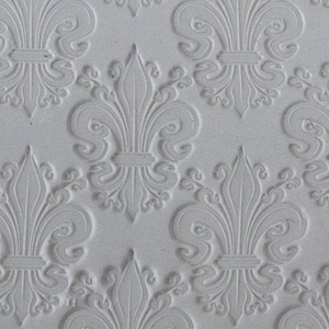 Puede incluir: Primer plano de una superficie blanca texturizada con un patrón repetitivo de diseños de flores de lis en relieve.