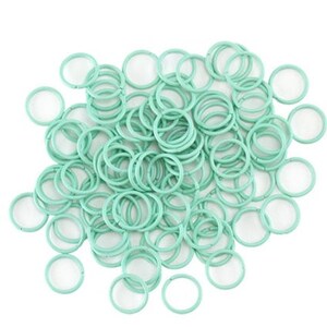 May include: A large pile of mint green jump rings. The rings are all the same size and are made of metal.