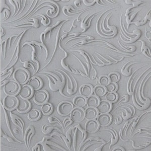 May include: A white embossed background with a repeating pattern of grapes and leaves. The pattern is raised and creates a textured surface.
