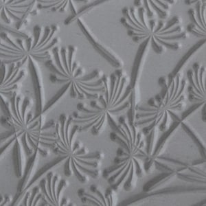 Puede incluir: Primer plano de una estera de hornear de silicona texturizada gris con un patrón repetitivo de flores estilizadas en relieve.