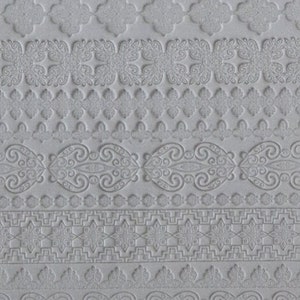 May include: A close-up of a light gray, textured surface featuring a repeating pattern of embossed decorative borders. The borders include floral, geometric, and scroll designs, creating a layered effect. The overall aesthetic is subtle and elegant.