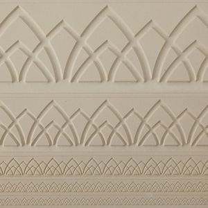 May include: A close-up of a white textured surface with three rows of embossed geometric patterns. The patterns are made up of repeating shapes that resemble arches and leaves.