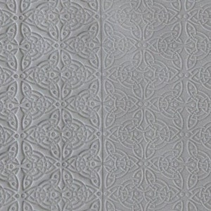 May include: A close-up of a gray textured surface with a repeating pattern of interlocking circles and lines. The pattern is embossed into the surface, creating a raised design.