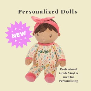 May include: A soft doll with brown hair and a pink headband, wearing floral pajamas. The doll is personalized with the name "Gwen" and the text "Personalized Dolls" is above the doll. A "NEW" starburst graphic is on the left.