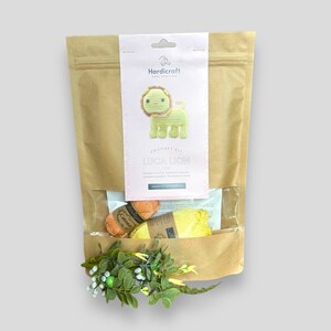 May include: A craft kit in a brown paper bag with a clear window, featuring a crochet lion. The kit includes yarn in orange and yellow, and the packaging reads "Luca Lion" and "Hardicraft Easy Crafting."
