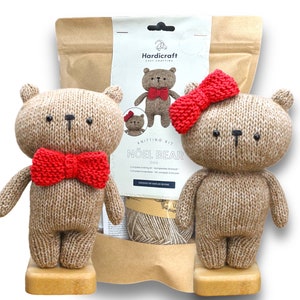 May include: Knitting kit for two brown teddy bears, one with a red bow tie and the other with a red bow. The kit includes yarn, needles, and instructions. The kit is called "Noël Bear" and is from the brand Hardicraft.