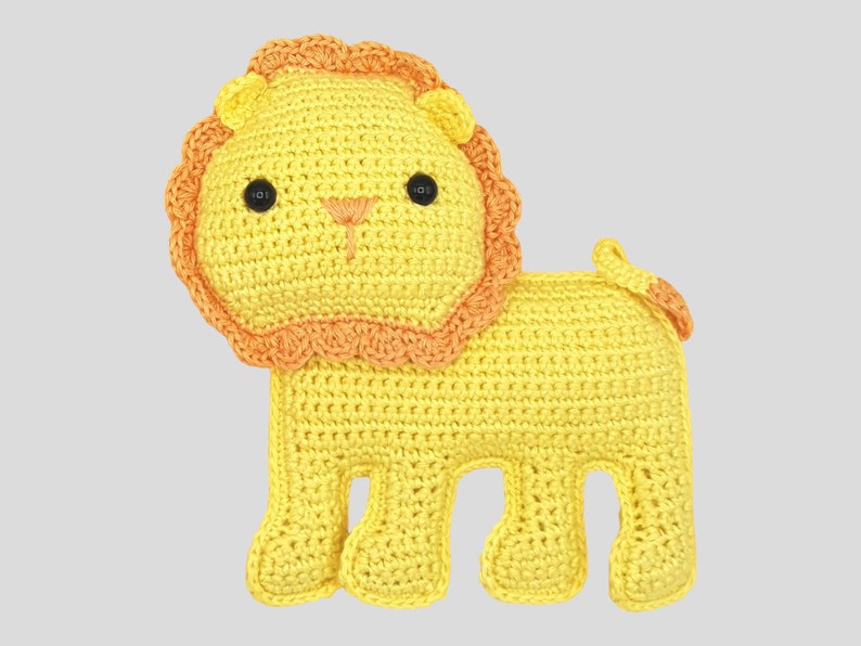 May include: A handmade crochet lion toy in yellow with an orange mane and tail. The lion has black button eyes and a stitched orange nose and mouth. The toy is designed with a friendly, cartoonish appearance.