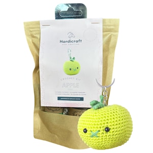 May include: A crochet kit to make a green apple keychain. The kit includes yarn, a crochet hook, and instructions. The finished apple keychain has a cute face with eyes and a mouth.