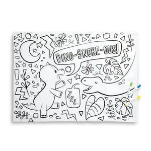 May include: A white coloring mat featuring a black and white dinosaur-themed design with the text "DINO-SNORE-OUS!". The mat includes illustrations of dinosaurs, stars, and plants. Three colored markers are visible.