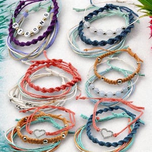 May include: Set of 10 colorful friendship bracelets with various charms, including beads, a heart, and the word "STRONG".