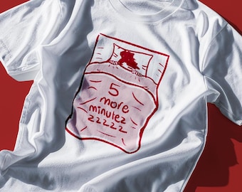 以下が含まれることがあります： 赤いイラストが描かれた白いTシャツ。ベッドで寝ている人が描かれており、"5分だけあと少しzzz"という文字が書かれている