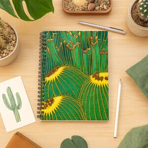 May include: A spiral-bound notebook featuring a vibrant green and yellow cactus pattern on the cover. The design displays multiple round cacti with prominent yellow centres and vertical green ribs, accented by thin gold lines throughout the artwork.
