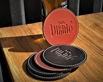 May include: Leather coasters in shades of brown and black with white stitching. The coasters feature the embossed text "PUB VIKING". A stack of coasters is visible, with one coaster standing upright.